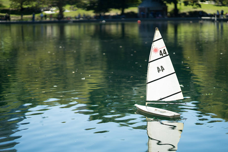 Miniature remote-controlled sail boat on the surface of a pond during a sunny day. Photograph by Oleksandra Korobova