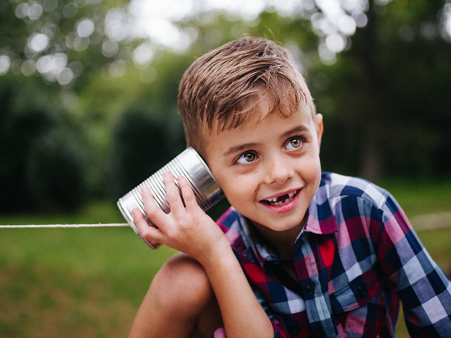 Mischievous Boy listening on tin can phone in his hands Photograph by Wundervisuals