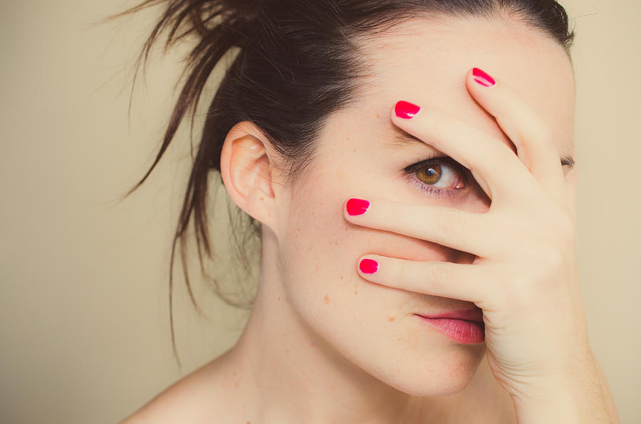 Misterious girl with red nails and hand on face. Photograph by Volanthevist