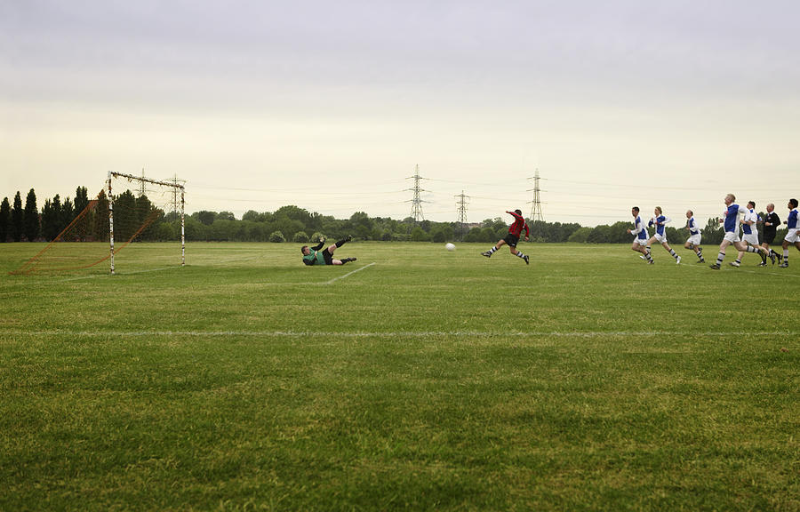 Mixed football match, opposing team chasing player towards goal Photograph by Anthony Marsland