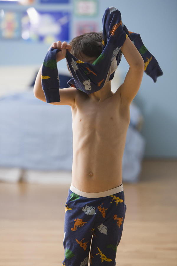 Mixed race boy putting on pajamas Photograph by Jose Luis Pelaez Inc