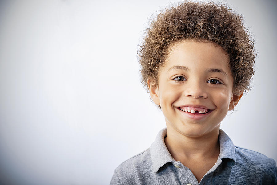 Mixed race boy with curly hair and missing tooth smiling Photograph by Jose Luis Pelaez Inc