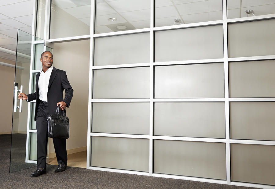 Mixed race businessman leaving modern office Photograph by Tanya Constantine