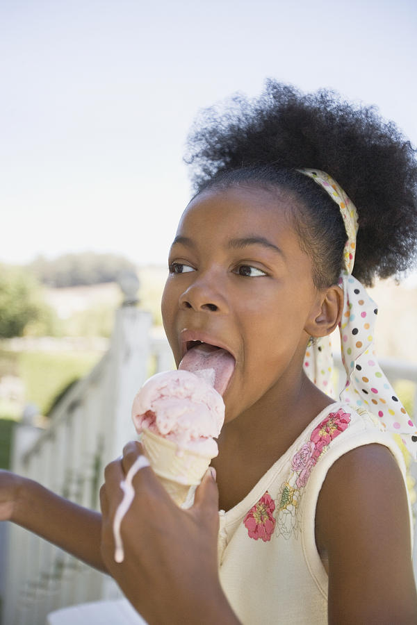 Mixed race girl licking melting ice cream cone Photograph by Annika Erickson
