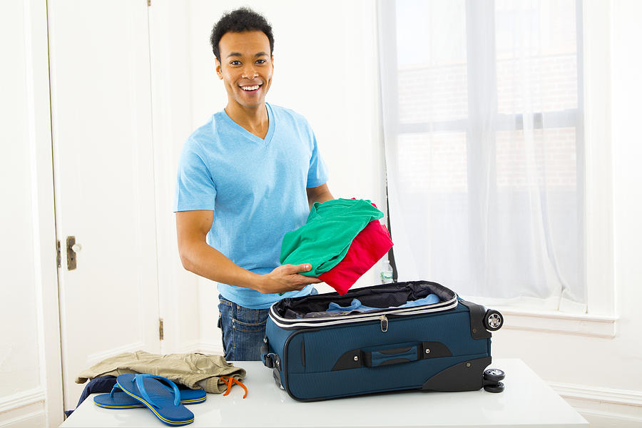 Mixed race man packing suitcase Photograph by Jason Homa