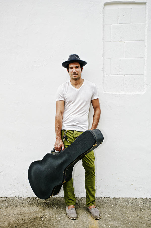 Mixed race musician carrying guitar case Photograph by Peathegee Inc