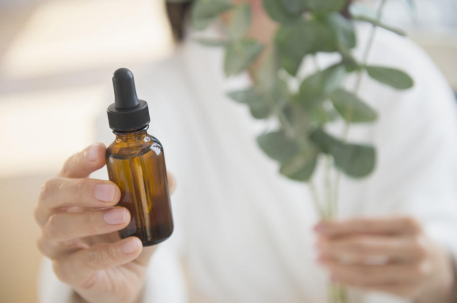 Mixed race woman holding bottle of essential oil Photograph by JGI/Jamie Grill