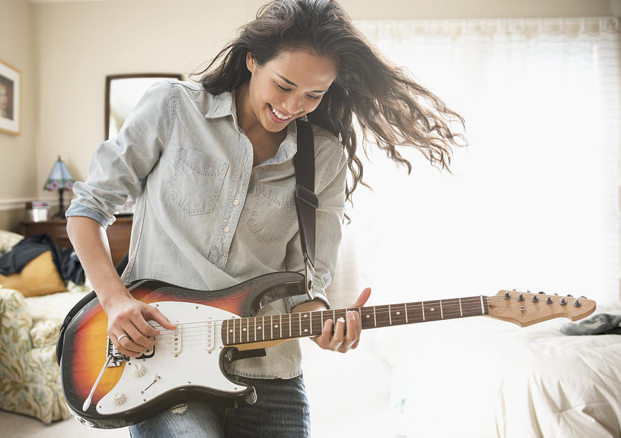 Mixed race woman playing electric guitar Photograph by Jose Luis Pelaez Inc