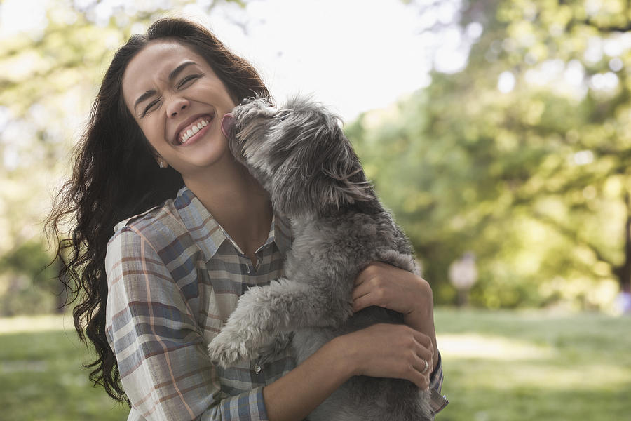 Mixed race woman playing with dog in park Photograph by Jose Luis Pelaez Inc