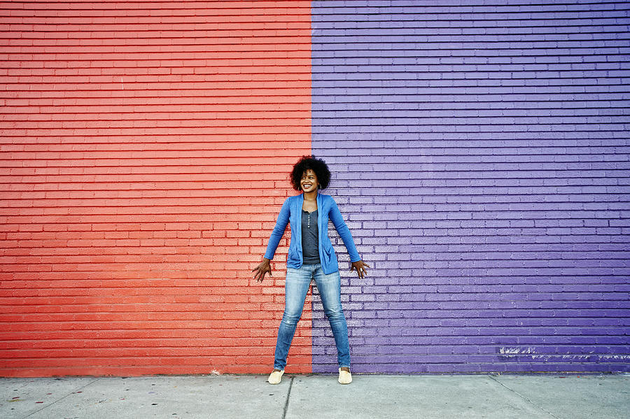 Mixed race woman standing by colorful wall Photograph by Peathegee Inc