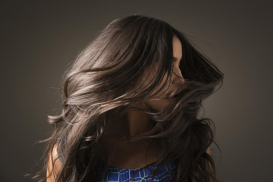Mixed Race woman tossing hair Photograph by Mike Kemp