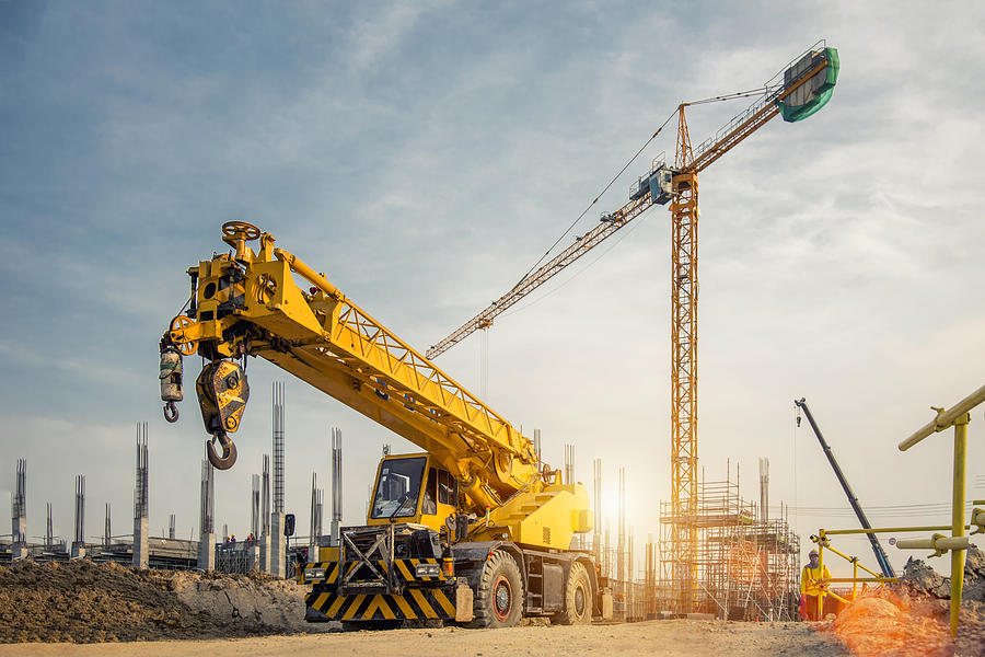 Mobile Crane on a road and tower crane in construction site Photograph by Jung Getty