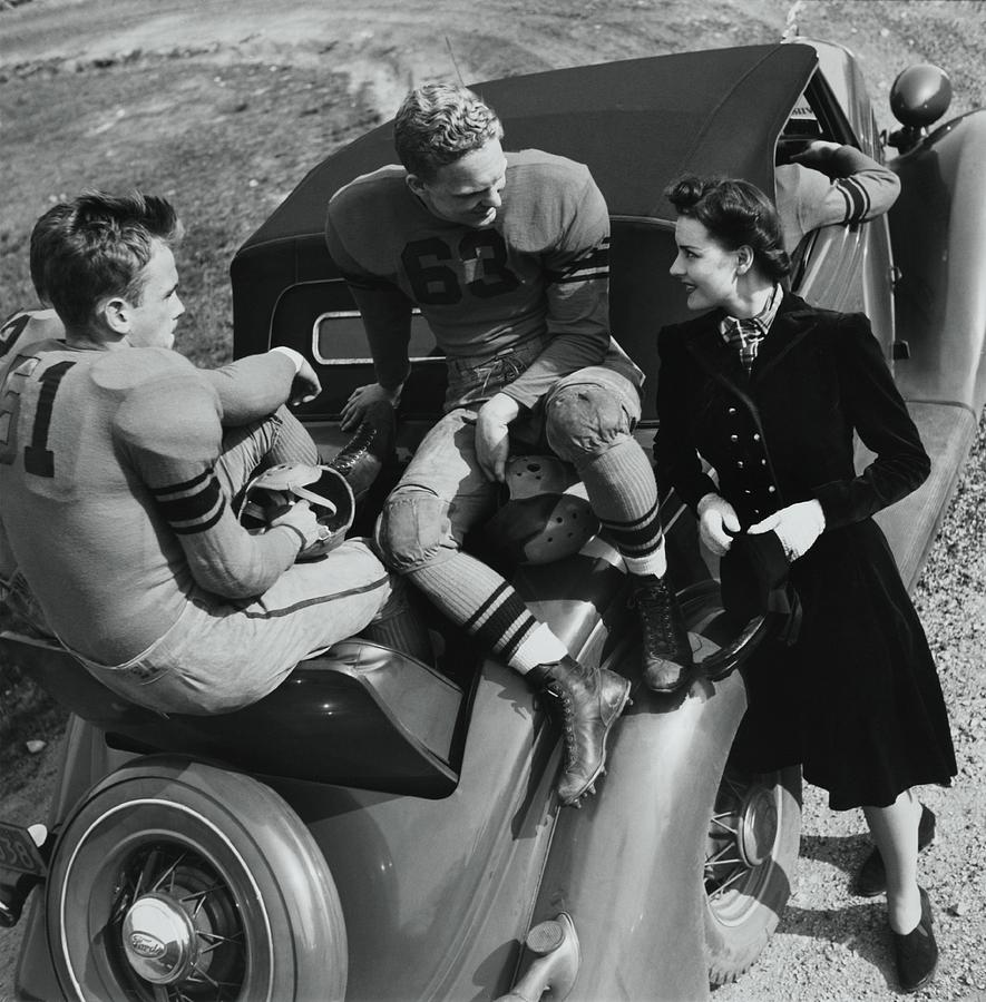 Model By Football Players On A Car Photograph by Toni Frissell