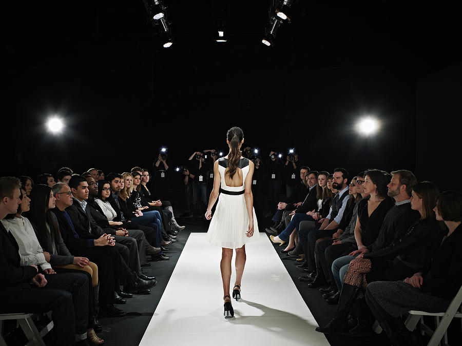 Model walking down catwalk during fashion show Photograph by Thomas Barwick