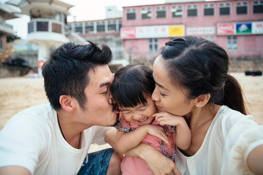 Mom & dad kissing lovely toddler girls cheek Photograph by images by Tang Ming Tung