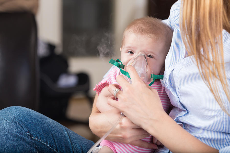 Mom giving nebulizer breathing treatment to sick infant baby Photograph by SDI Productions