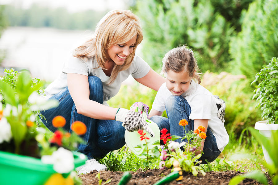 Mother and daughter planting flowers together Photograph by Skynesher