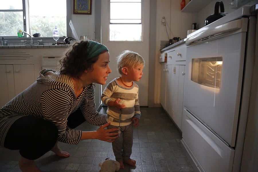 Mother and son looking in oven window Photograph by Pixelchrome Inc