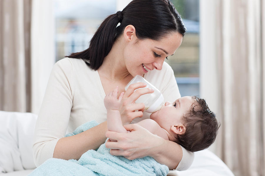 Mother bottle feeding baby boy Photograph by Image Source