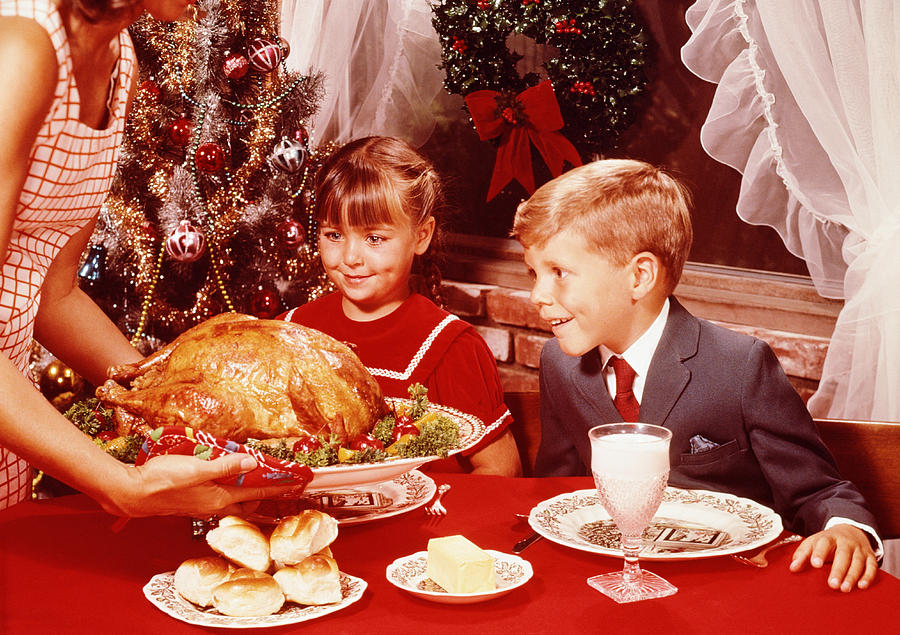Mother showing roast turkey to children (7-10) at Christmas meal Photograph by Fpg