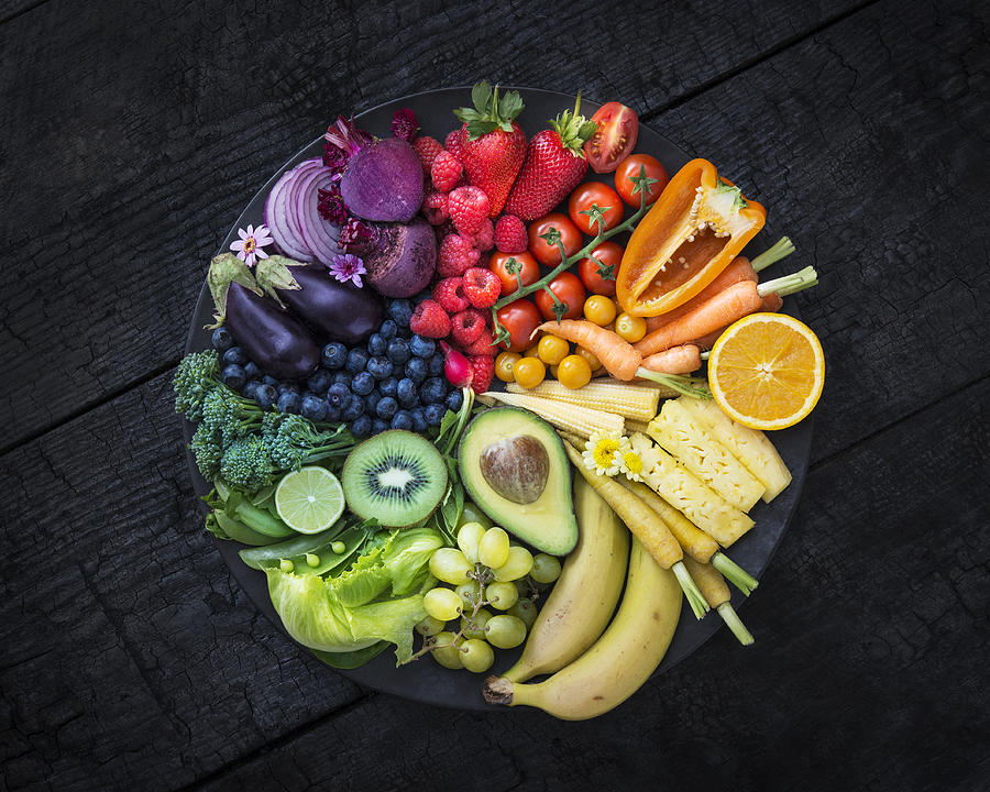 Multicoloured fruit and vegetables in a black bowl on a burnt surface. Photograph by David Malan
