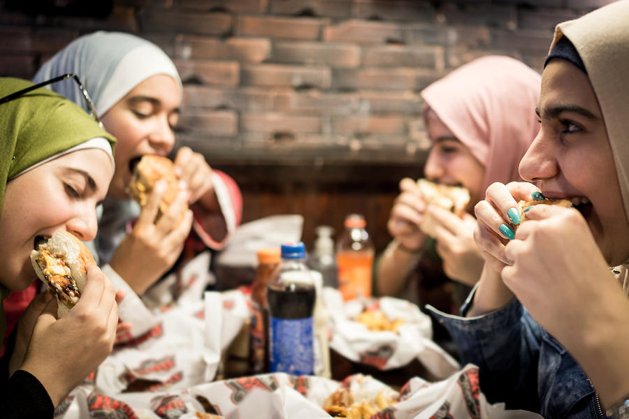 Muslim teenage girls having a lunch break together in restaurant Photograph by Jasmin Merdan