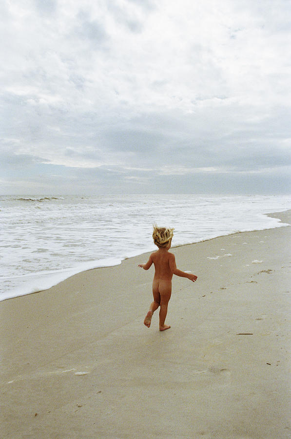 Naked boy (2-4) running on beach, rear view Photograph by Blaise Hayward