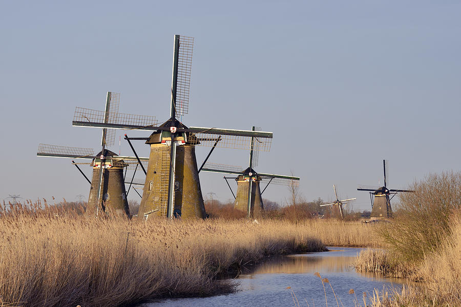 Netherlands, South Holland, Kinderdijk, Windmills at a canal with warm morning light Photograph by Westend61