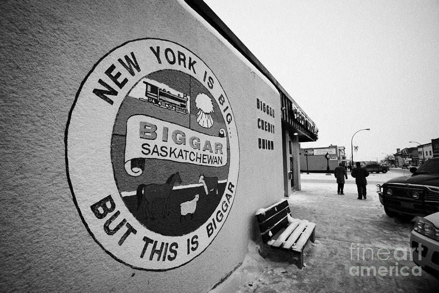 Winter Photograph - new york is big but this is biggar slogan sign Biggar main street Saskatchewan Canada by Joe Fox