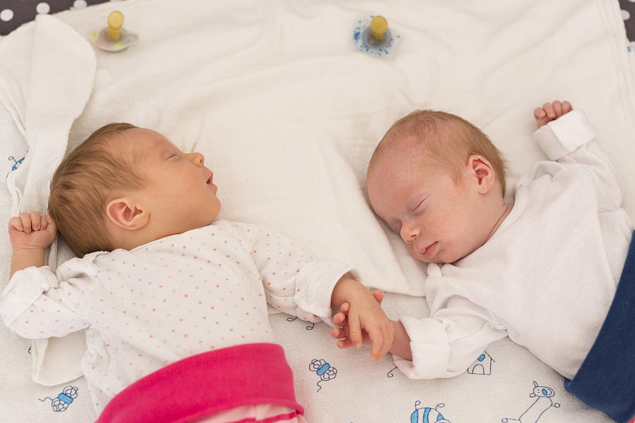 Newborn twins sleeping hand in hand Photograph by Westend61