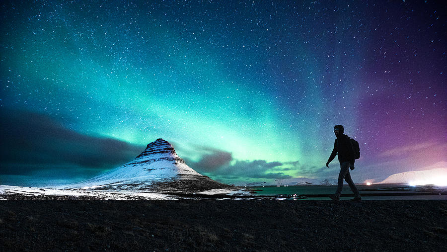 Northern lights in Mount Kirkjufell Iceland with a man passing by Photograph by LeoPatrizi