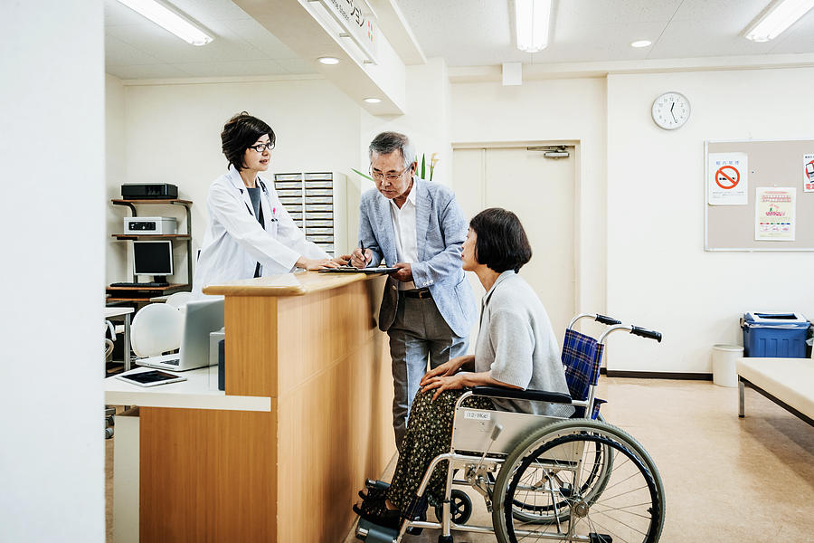 Nurse Helping Elderly Couple At Hospital Counter Photograph by TommL