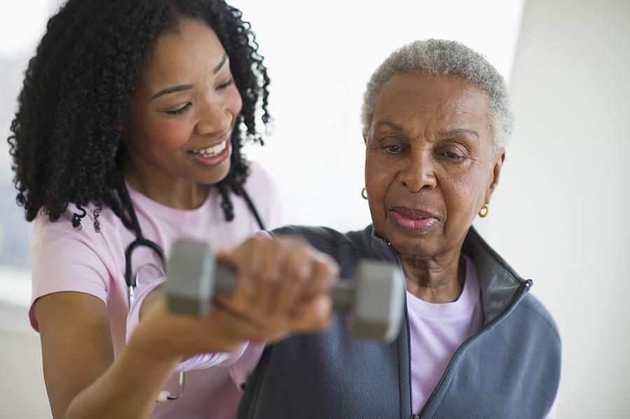 Nurse helping woman exercise with dumbbell Photograph by Blend Images - JGI/Tom Grill