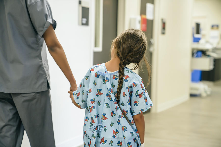 Nurse holding hands with girl in hospital Photograph by FS Productions