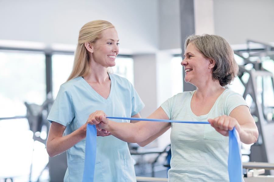 Nurse Showing Woman How To Use Resistance Band by Science Photo Library