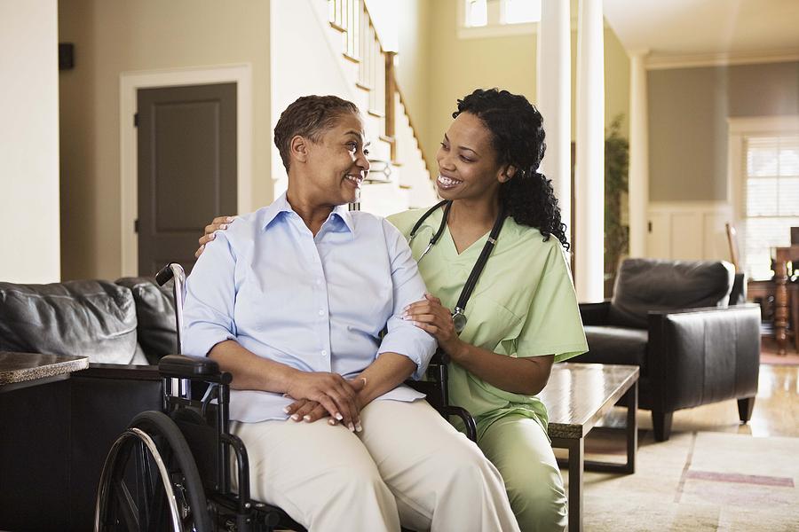 Nurse with woman in wheelchair at home Photograph by Jupiterimages