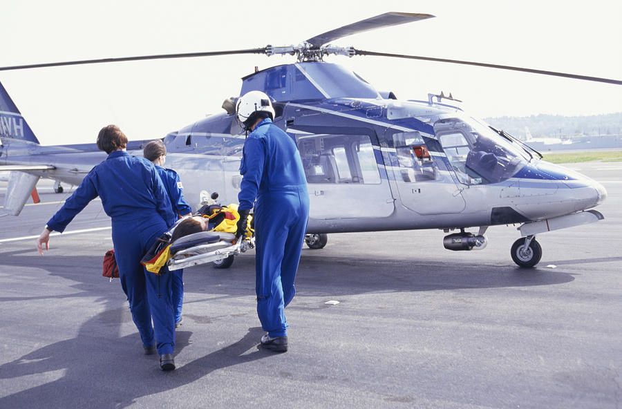 Nurses and pilot carrying patient on stretcher to helicopter Photograph by Keith Brofsky