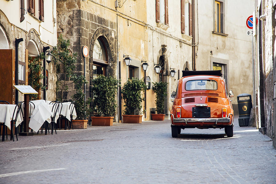 Old red vintage car on the narrow street in Italy Photograph by Alexander Spatari