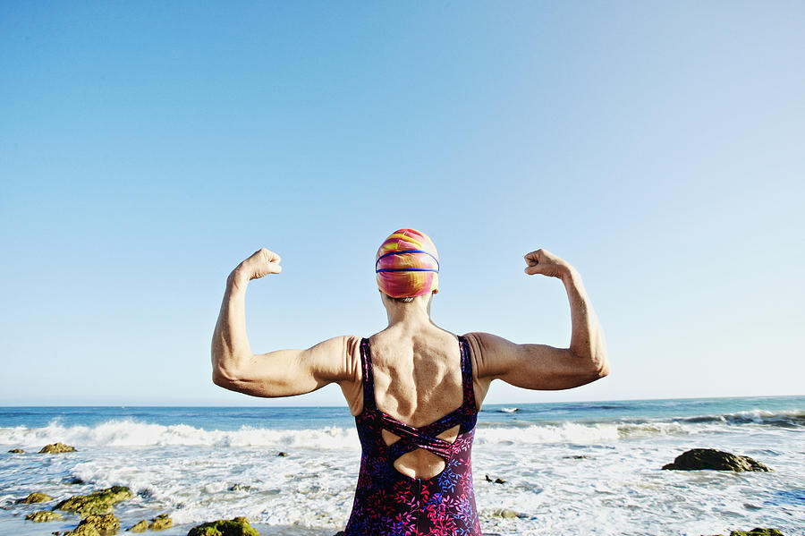 Older Caucasian woman flexing her muscles on beach Photograph by Peathegee Inc