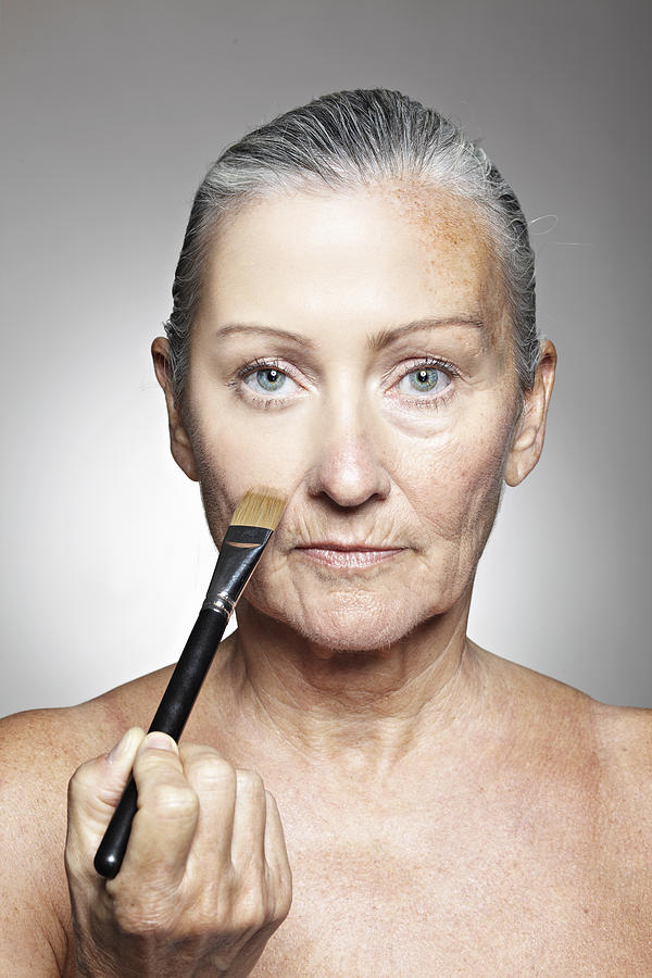 Older woman smoothing her face Photograph by Cultura RM Exclusive/Liam Norris