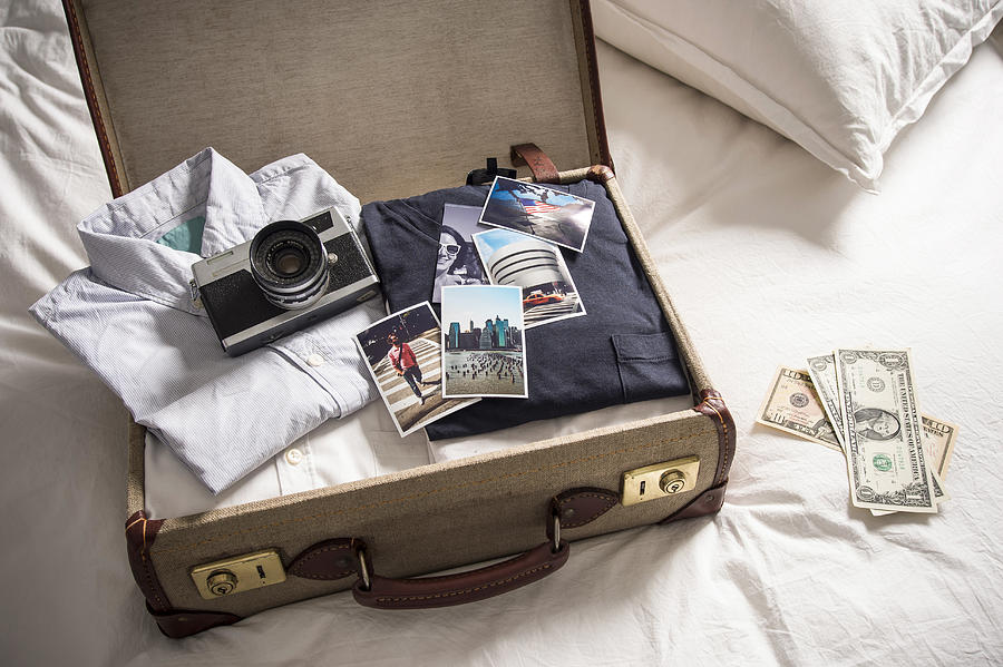 Open suitcase on bed with camera and photographs Photograph by David Cleveland