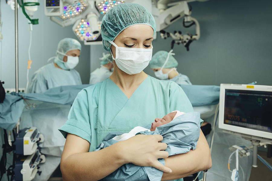 Operating room nurse holding newborn in operating room Photograph by Westend61