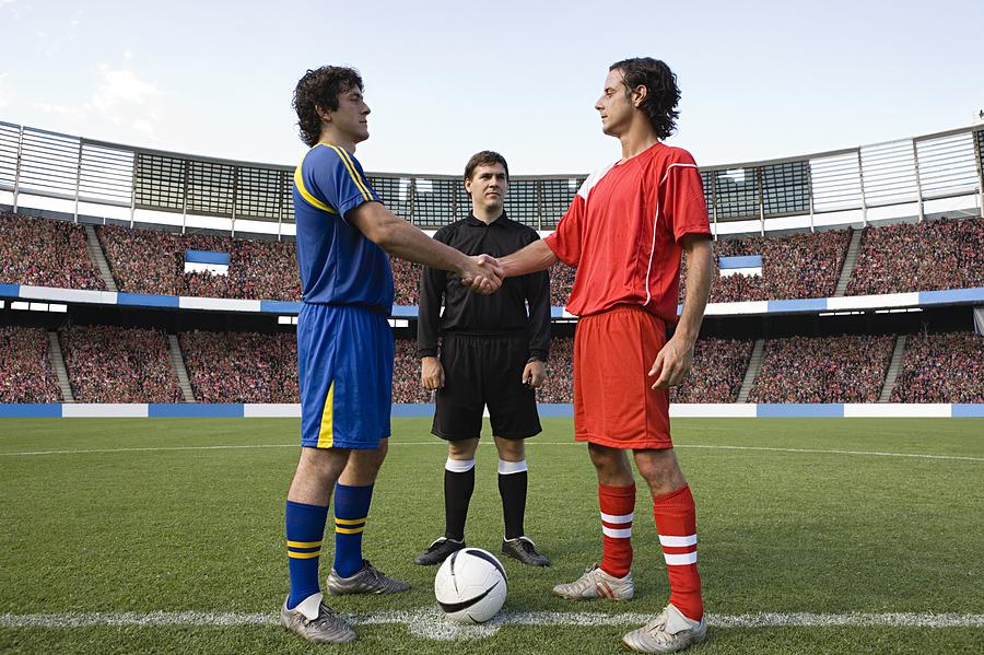 Opposite football player shaking hands Photograph by Image Source