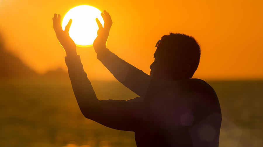 Optical Illusion Of Man Holding Sun At Beach During Sunset Photograph by Kryssia Campos