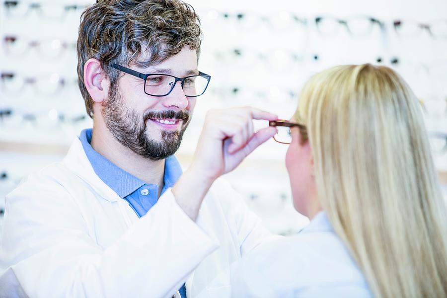 Optometrist Trying Glasses On Woman Photograph By Science Photo Library