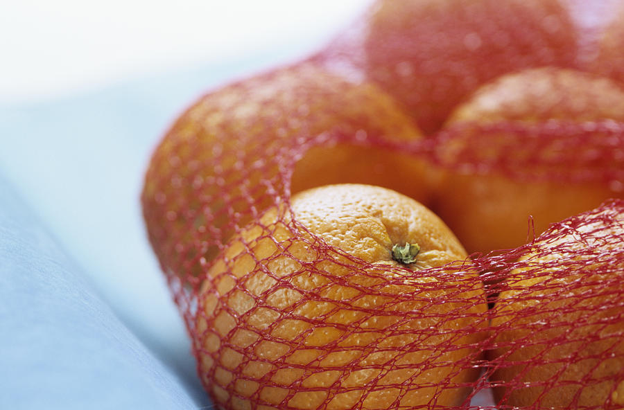 Oranges in net, close up Photograph by Achim Sass