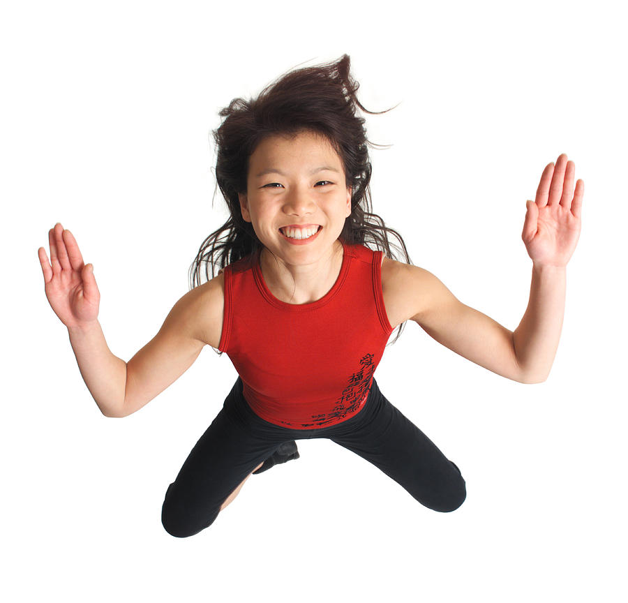 Overhead View Of An Attractive Asian Girl In A Red Tank Top And Black Pants Crouched Down And Spreads Her Arms Out As She Looks Up Into The Camera Photograph by Photodisc