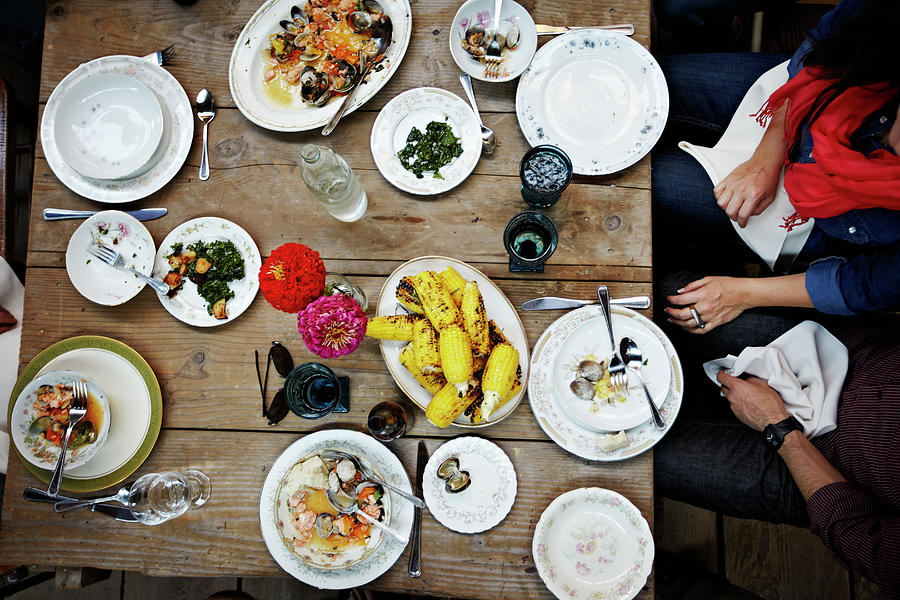 Overhead View Of Friends Dining Mid-meal Photograph by Thomas Barwick