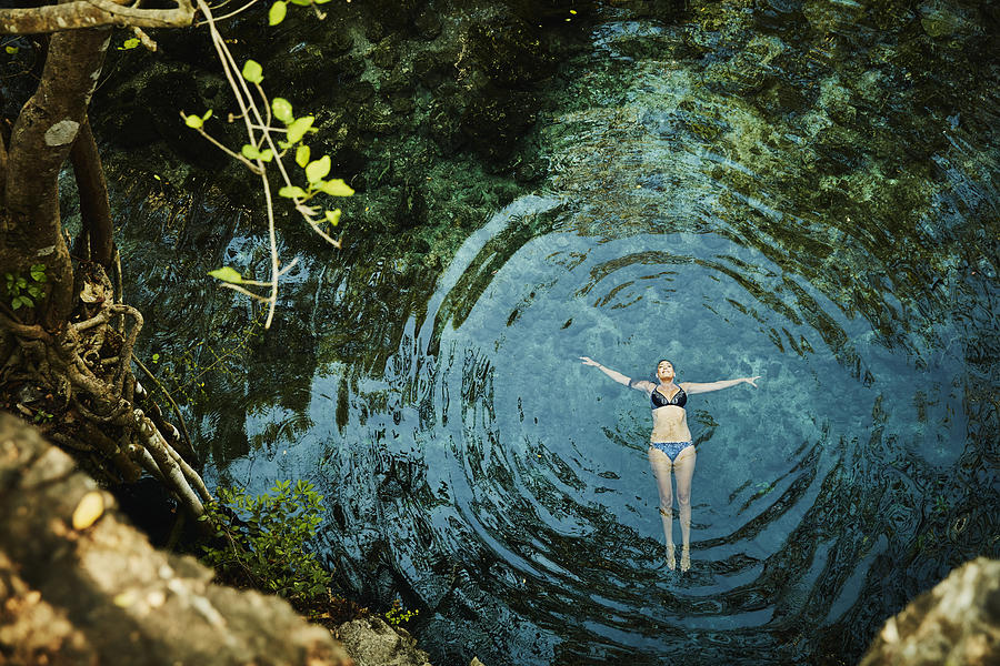 Overhead view of woman floating on back in cenote while on vacation Photograph by Thomas Barwick