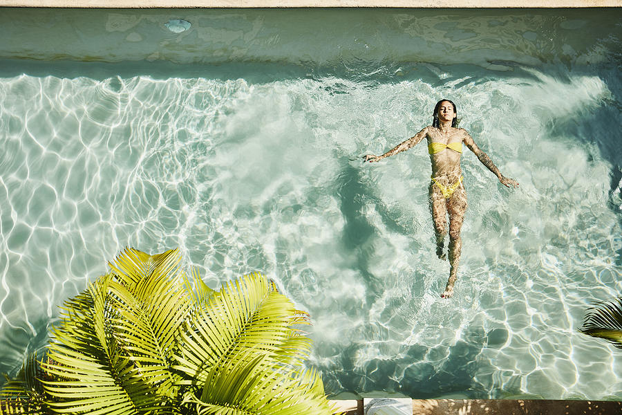 Overhead view of woman floating on her back in pool at outdoor spa Photograph by Thomas Barwick